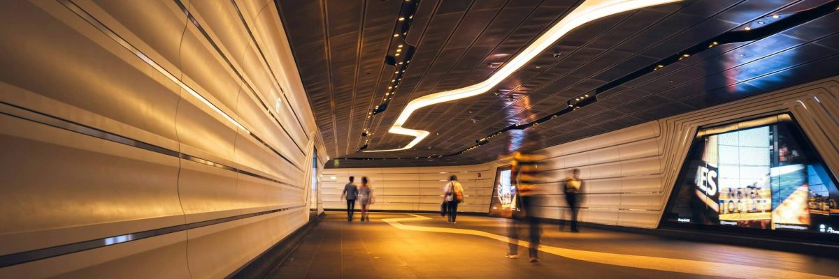 Commuters walking through a futuristic looking pedestrian tunnel featuring an LED integrated lights